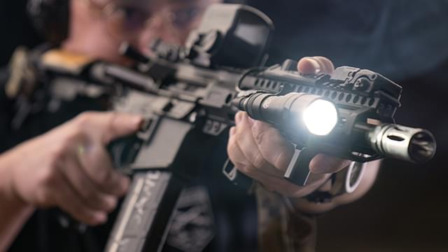 Man shooting a rifle with a flashlight
