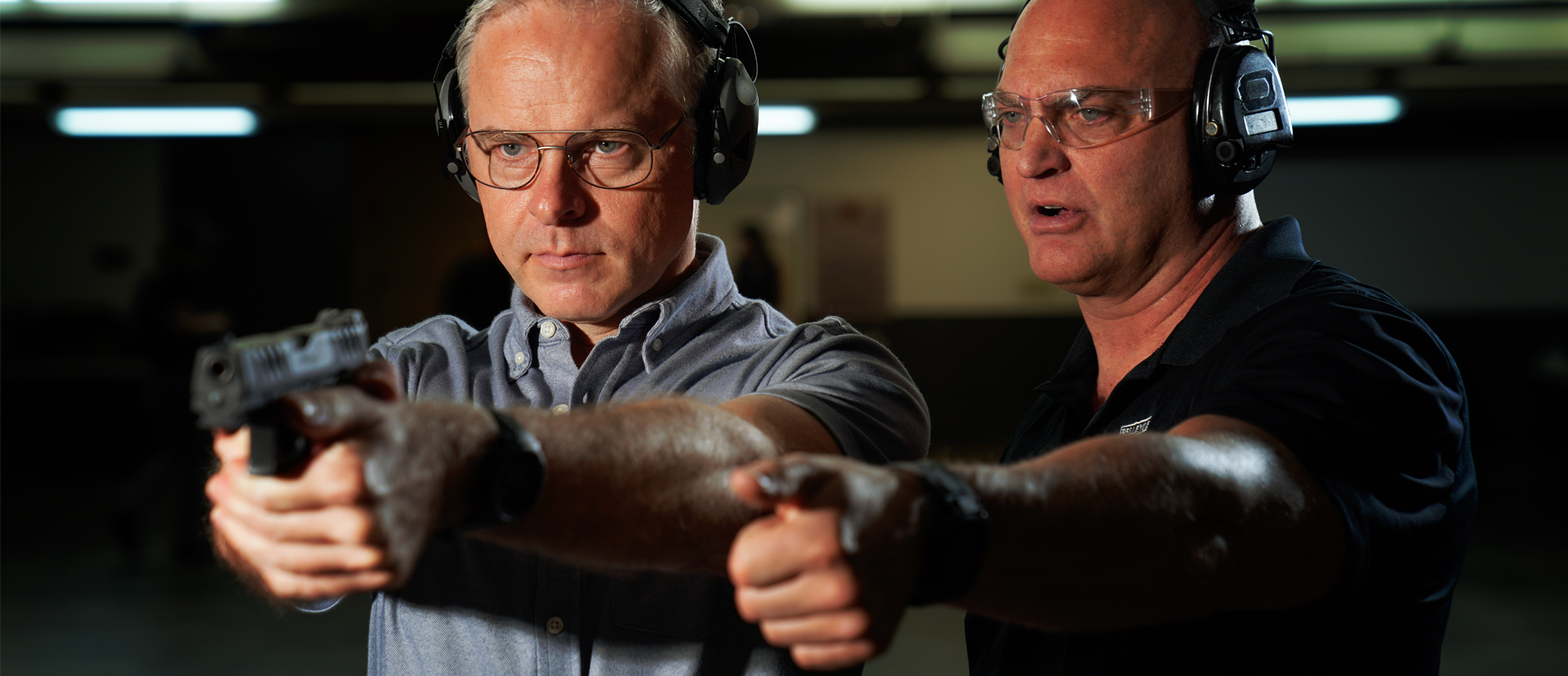 One man teaching another how to shoot a firearm