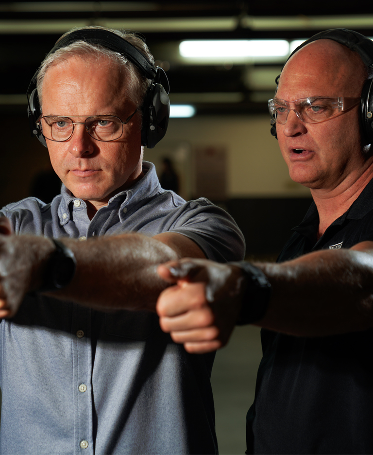 One man teaching another how to shoot a firearm